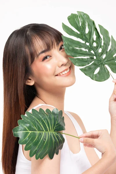 年轻美丽的亚洲女人面带微笑 肌肤洁白清新 绿叶覆盖 与白色背景 美容美发及温泉护理理念隔离 — 图库照片