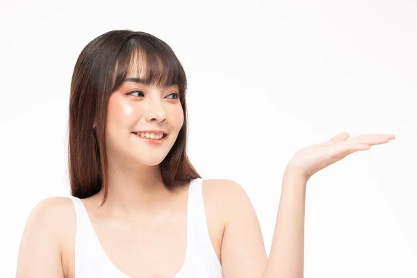 美しい魅力白い歯を持つアジアの若い女性の笑顔を開いて手ヤシのディスプレイ化粧品製品健康的な肌で陽気に 白い背景に孤立 美容化粧品コンセプト — ストック写真