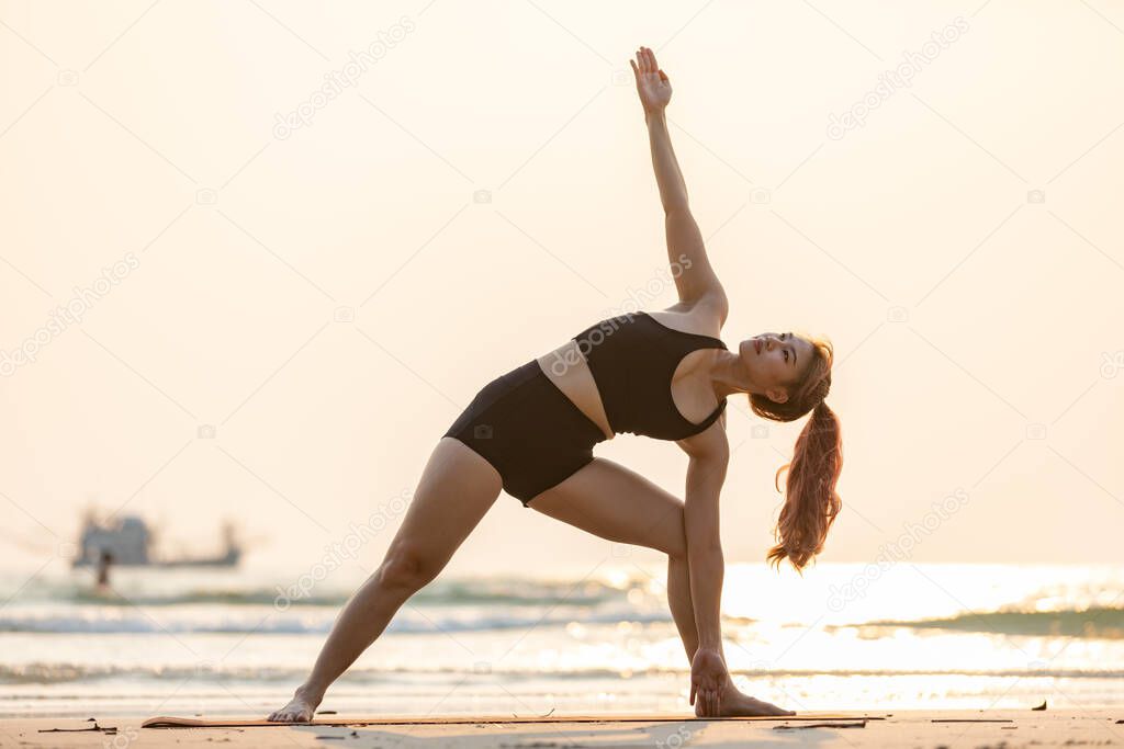 woman practice yoga Triangle pose to meditation summer vacation on the the beach,Travel in tropical beach Thailand,vacations and relaxation Concept