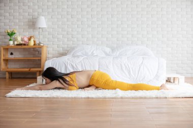Mutlu Atletik Asyalı kadın, sabah uyandıktan sonra meditasyon gülümsemesiyle ısınmak için kaslarını esnetme hareketi yapıyor. Kendini çok rahat ve rahat hissediyor.