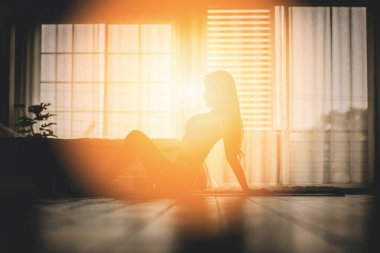 Silüet atletik kadın yoga yapıyor ısınmak için kaslarını esnetiyor sabah uyandıktan sonra meditasyon tebessümüyle kendini çok rahat ve rahat hissediyor, sağlık sigortası kavramı