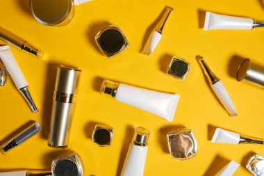 Sarı zemin üzerine kurulmuş düz kozmetik ürünleri, boş beyaz tüp ve şişe kozmetik ürünleri manzarası yaz tatiline hazır güneş ışığı, Güzellik Konsepti