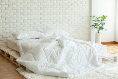 Yatağı beyaz yastıkla, battaniyeyi de yatak odasında doğal ışıkla, yatağı da dağınık, yatak odası da dağınık.