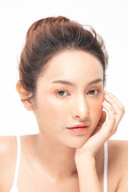 Güzel Asyalı kadın yumuşak yanaklı gülüşüne dokunuyor. Temiz ve taze tenli. Mutluluk ve neşe, olumlu duygusal, beyaz arka planda izole edilmiş.