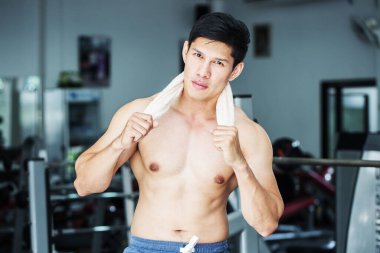 Yakışıklı Asyalı erkekler spor salonunda çalıştıktan sonra gülümser. Sakinleşir ve kaslarını gevşetir. Vücut geliştirici kavramı.
