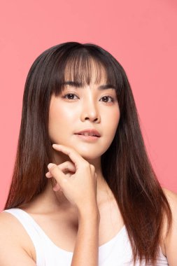 Genç ve güzel Asyalı kadın gülümsüyor yumuşak yanağa dokunuyor temiz ve taze tenli mutluluk ve neşe olumlu duygusal, pembe arka planda izole edilmiş güzellik kozmetik ve kaplıca konsepti