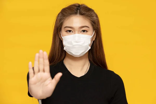 コロナウイルスや大気汚染から身を守るマスクを身に着けている女性ストップハンドサイン黄色の背景に隔離された ヘルスケアコンセプト — ストック写真