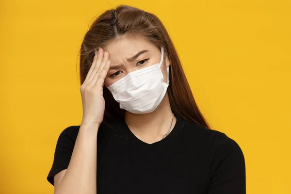 黄色の背景に保護されたウイルスや大気汚染のための保護マスクや外科マスクを身に着けているアジアの女性 女性は発熱などの頭痛を持っています ヘルスケアとコロナウイルスの概念 — ストック写真