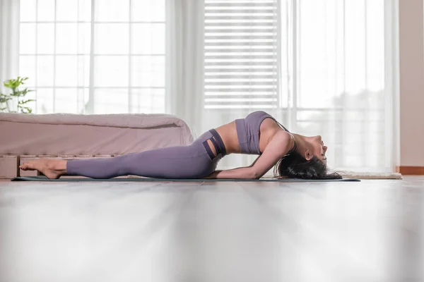 Beautiful Attractive Asian woman practice yoga Fish or yoga Matsyasana pose to meditation with yoga in bedroom,Recreation in holidays concept