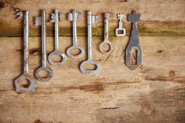 Eski anahtarlar eski ahşap bir yüzeyde yatıyor. Ahşap dokular soyulmuş yeşil boyalardan görülebiliyor..