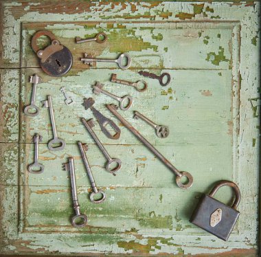 Eski ahşap bir yüzey üzerinde eski bir anahtar deliği ve eski vintage anahtarlar bulunan eski bir kilit. Ahşap dokular soyulmuş yeşil boyalardan görülebiliyor..