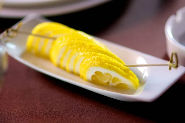 A juicy bright lemon cut into slices lies on a white plate. This healthy fruit is always in great demand in famous restaurants around the world.