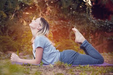 Kız yoga yapıyor. Park yeşilliği meditasyonu, spor sağlığı, evde yoga.