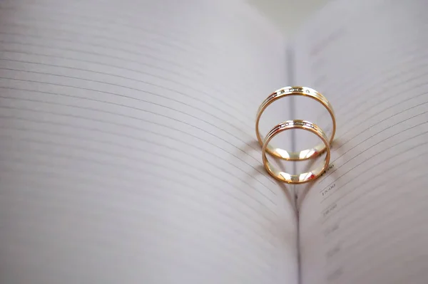 Two gold rings lie on the page of the book. Beautiful wedding day, rings in the diary.