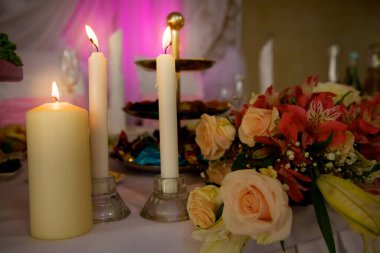 Masada beyaz ve pembe çiçeklerin yanında mumlar yanıyor. Düğün iç dekorasyonu bir restoranda masa dekorasyonu.