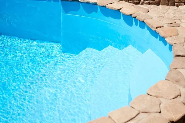 A great summer day by the pool at home with clear blue water. A deep pool on the edge of the overlaid decorative stone, photo horizontal background, commercial swimming pools hotels