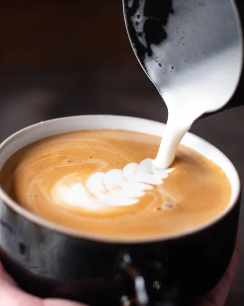 Beautiful Latte Art in process. Milk pour in the cup of espresso.