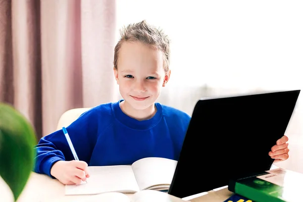 Roztomilý Usmívající Chlapeček Modrém Saku Tabletkou Ruce Sedí Stolu Dělá — Stock fotografie