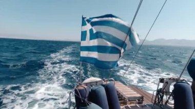 Yazın, okyanusun ortasında Yunanistan Boğazı 'nda bir tekneyle denize açılmak. Sıcak rüzgarlı hava teknede dalgalanan Yunanistan bayrağını yaptı.