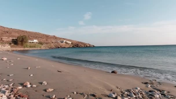 砂の中に多くの岩があるティノス島のオルモス ジャンナキ ビーチの海岸風景風の強い天候がビーチに波を吹く — ストック動画