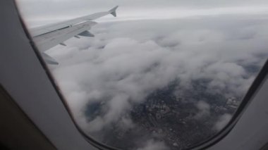 Açık bir günde Birleşik Krallık 'ın kırsalında uçmak. Kalın bulutların arasından uçak penceresinden bak