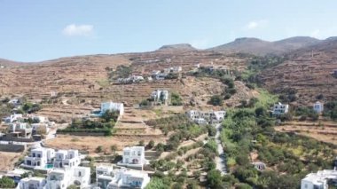 Yunanistan 'ın Tinos kentindeki tepede çok az sayıda ev bulunan kuru dağ manzarasına doğru insansız hava aracı uçuşu