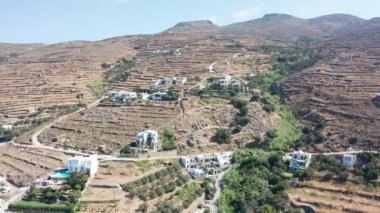 Yunanistan 'ın Tinos kentindeki tepede çok az sayıda ev bulunan kuru dağ manzarasına doğru insansız hava aracı uçuşu