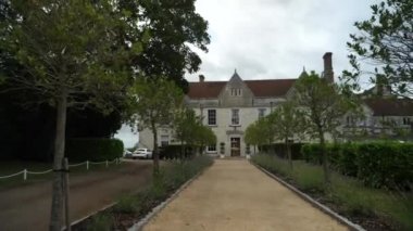 Küçük ağaçların arasında, taşrada büyük bir malikaneye doğru giden çakıllı bir yolda geziniyor.