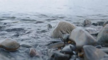 Akşamları kayalık sahilde yumuşak deniz dalgaları dalgalanır..