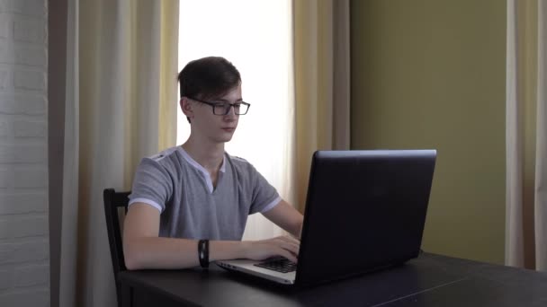 Adolescente Trabajador Con Gafas Está Sentado Una Mesa Haciendo Los — Vídeo de stock