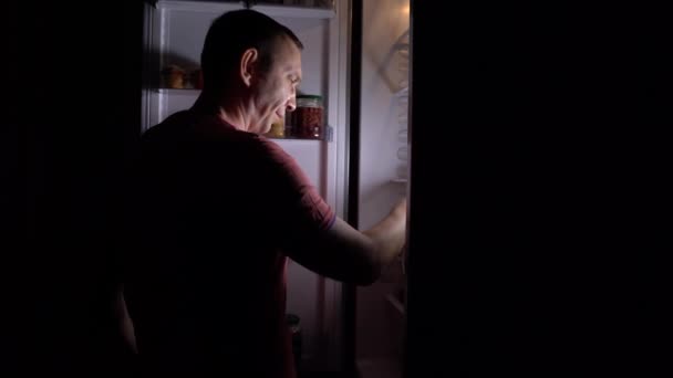 4K撮影 お腹を空かせた中年の男が夜になると台所に来て食事をする 夜の冷蔵庫から空腹とグルトニー 適切な栄養 グルトニー 健康の概念 — ストック動画