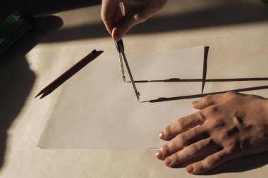 Tasarımcının işyeri. Pusula tutan bir adamın eli. Beyaz sayfa