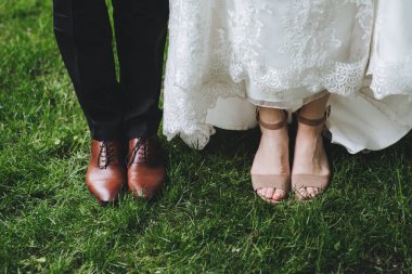 Gelinle damadın ayakları, düğün ayakkabıları. Yeşil çimlerin üzerinde.