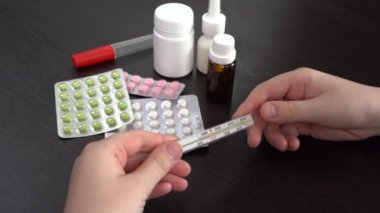 4 bin. Genç adam termometreye bakıyor. Karanlık bir masada haplar ve beyaz kutular var..