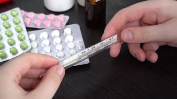 Jovem Olhar Para Termómetro Uma Mesa Escura Pílulas Caixas Brancas — Vídeo de Stock