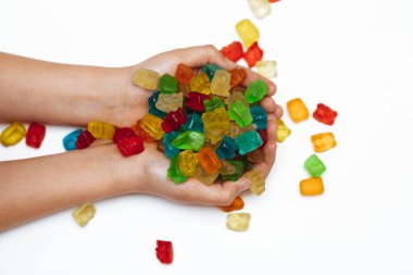 Beyaz arka planda kadın elleri ayı şeklinde marmelat tutar.