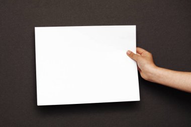 Kadın eli, arka planda beyaz bir kağıt tutuyordu.