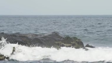 4 bin. Kıyı şeridi. Büyük, köpüklü bir dalga, kıyıya vuruyor, spreye dönüşüyor. Doğanın inanılmaz gücü. .