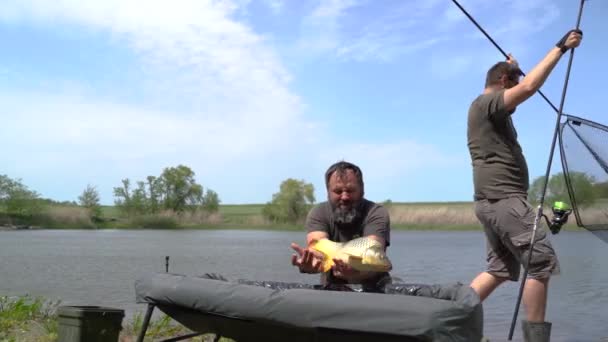 渔夫钓到了一条鱼 他高兴地看着钓到的鱼 阳光明媚的夏日 风景如画 成功捕鱼的好时机 — 图库视频影像
