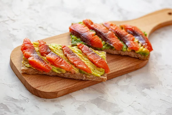 Duas Sanduíches Com Peixe Vermelho Abacate Tábua Corte Madeira — Fotografia de Stock