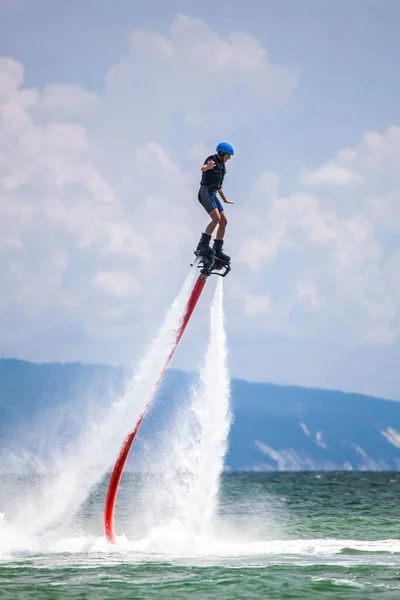 Young woman is flying at the aquatic flyboard. Water extreme sport