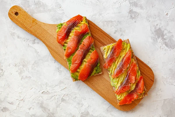 Duas Sanduíches Com Peixe Vermelho Abacate Tábua Corte Madeira — Fotografia de Stock