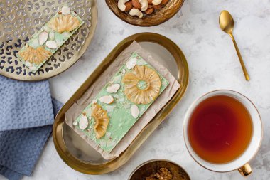 El yapımı yeşil çikolata, ananas, hindistan cevizi ve badem bir fincan çayın yanında duruyor.