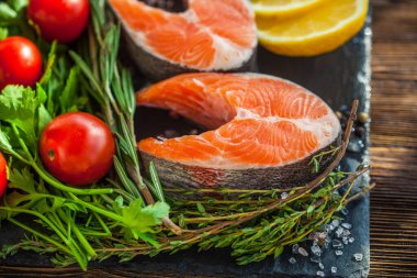 İki tane yeşil somon bifteği, limon ve vişneli domates.