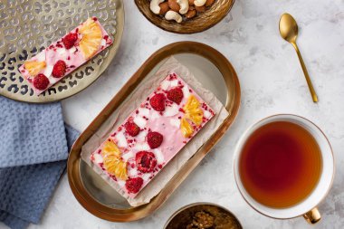 El yapımı pembe çikolata, ananas, çilek ve hindistan cevizi bir fincan çayın yanında duruyor.