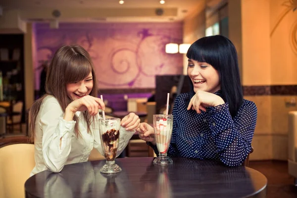 Bayan arkadaşlar kafede konuşuyor ve gülüyor.