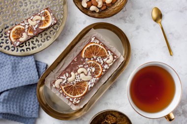 Portakal dilimli el yapımı çikolatalı, kabarık pirinçli ve fındıklı çay fincanının yanındaki masada.