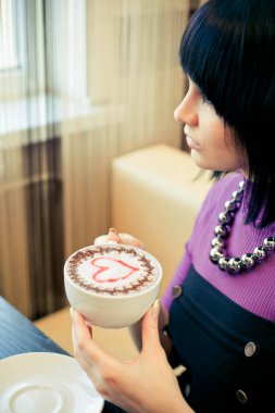 Elinde kahve tutan genç bir kadın.