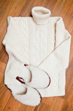 Kadın yerde yün süveter ve tüylü terlikler örüyordu.