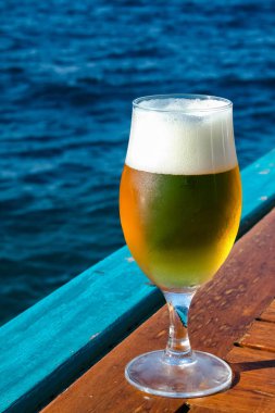 Mavi denizin arka planında bir bardak soğuk bira